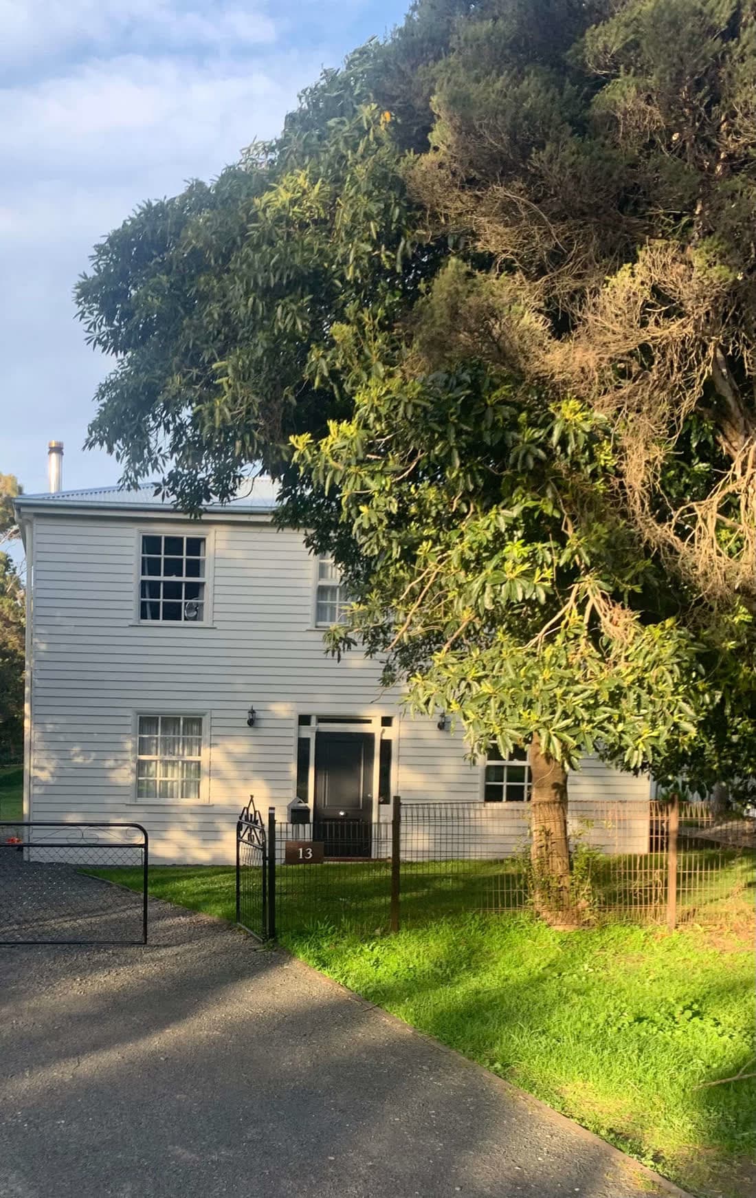 The finished two-storey weatherboard house, viewed from the front garden in late afternoon light.